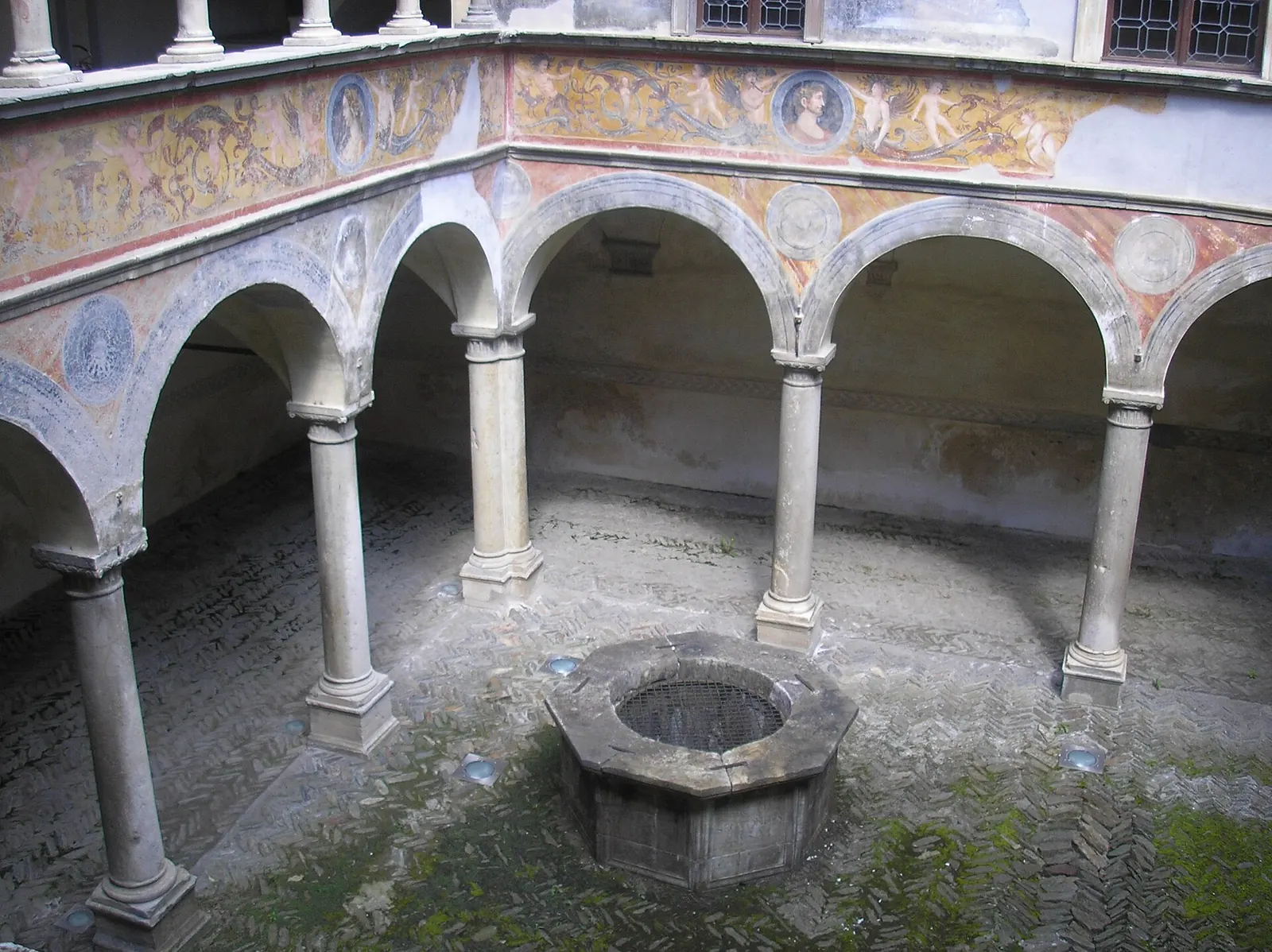 Il cortile porticato di Palazzo Besta a Teglio, con archi, colonne e un pozzo ottagonale al centro
