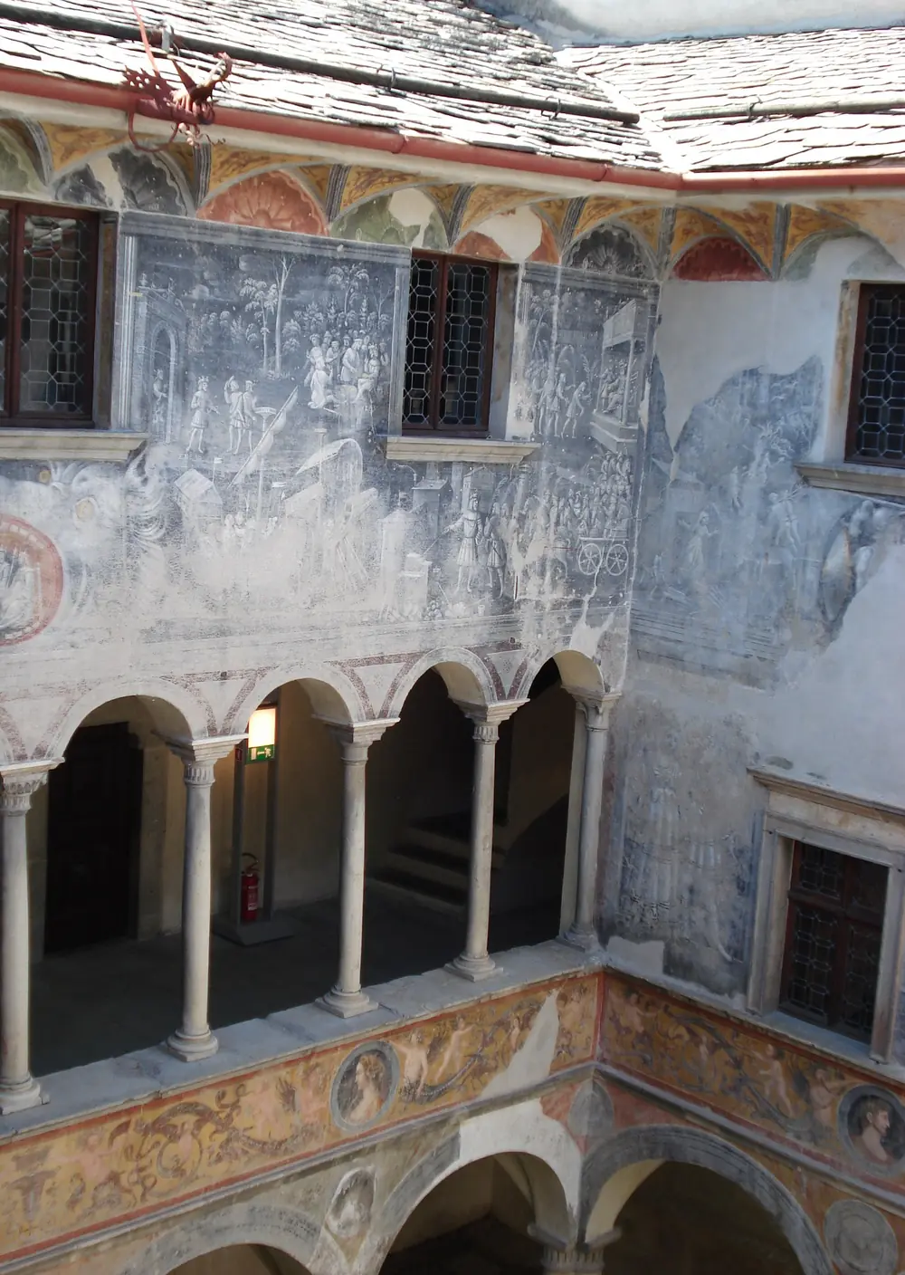 Il loggiato a più piani del cortile di Palazzo Besta, con arcate, colonne sottili e muri affrescati